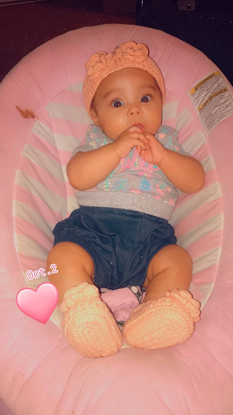 Neveah is registered to the contest to win money with this photo: baby, baby_toddler_clothing, cheek, child, comfort, face, facial_expression, finger, headwear, knee, leg, mouth, nose, person, pink, skin, sleeve, sock, stomach, surprise