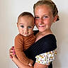 Cash is registered to the contest to win money with this photo: child, baby, smile, holding, portrait, face, blue_eyes, brown_hair, braided_hair, long_sleeve, patterned_clothing, earrings, necklace, indoor, closeup, person, cute, happy, family, toddler