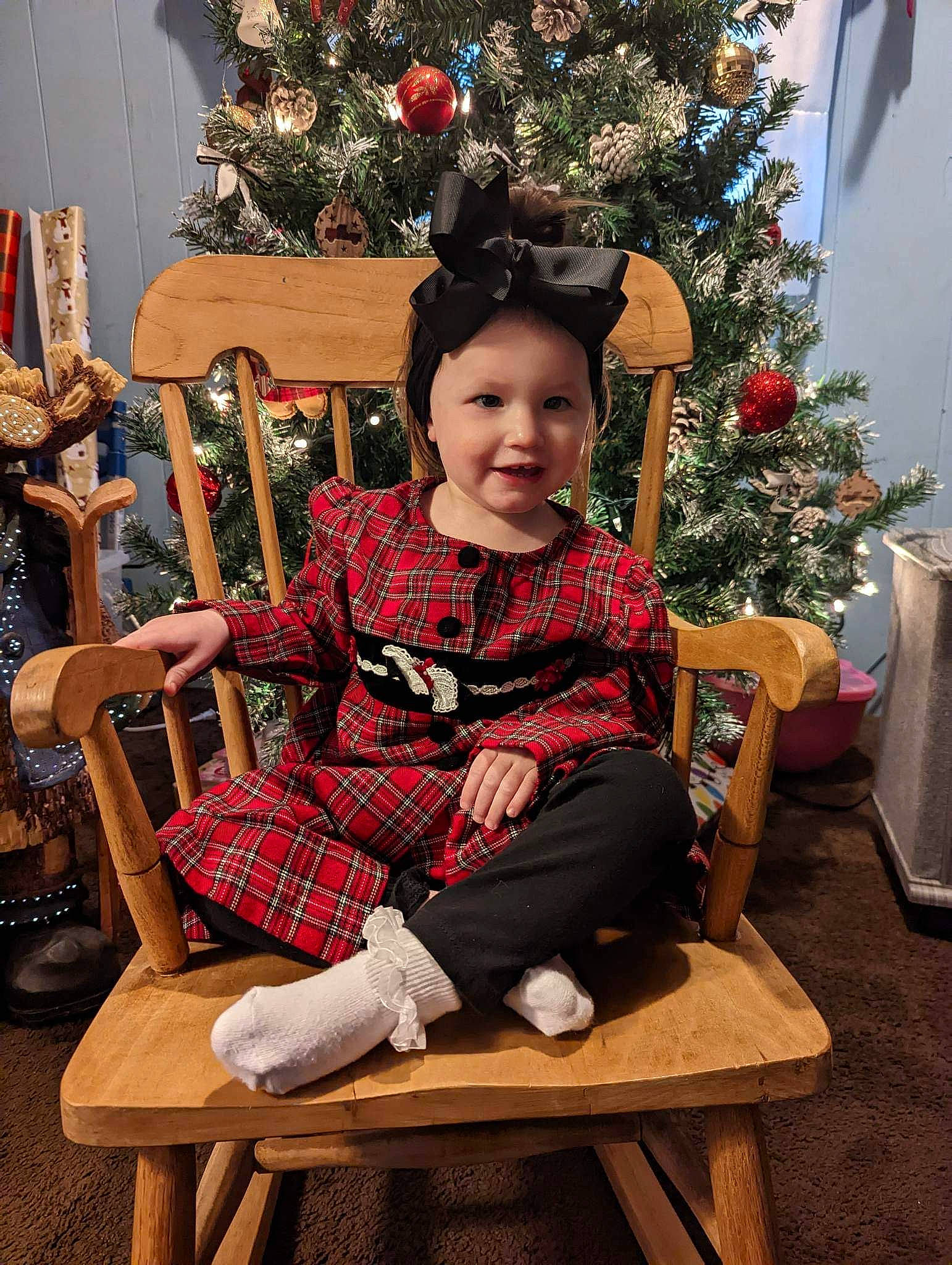 Nylah joined the competition — help win amazing prizes! chair, christmas, christmas_decoration, christmas_ornament, christmas_tree, comfort, event, fun, furniture, happy, headwear, holiday, holiday_ornament, lap, person, sitting, sleeve, smile, standing, tartan