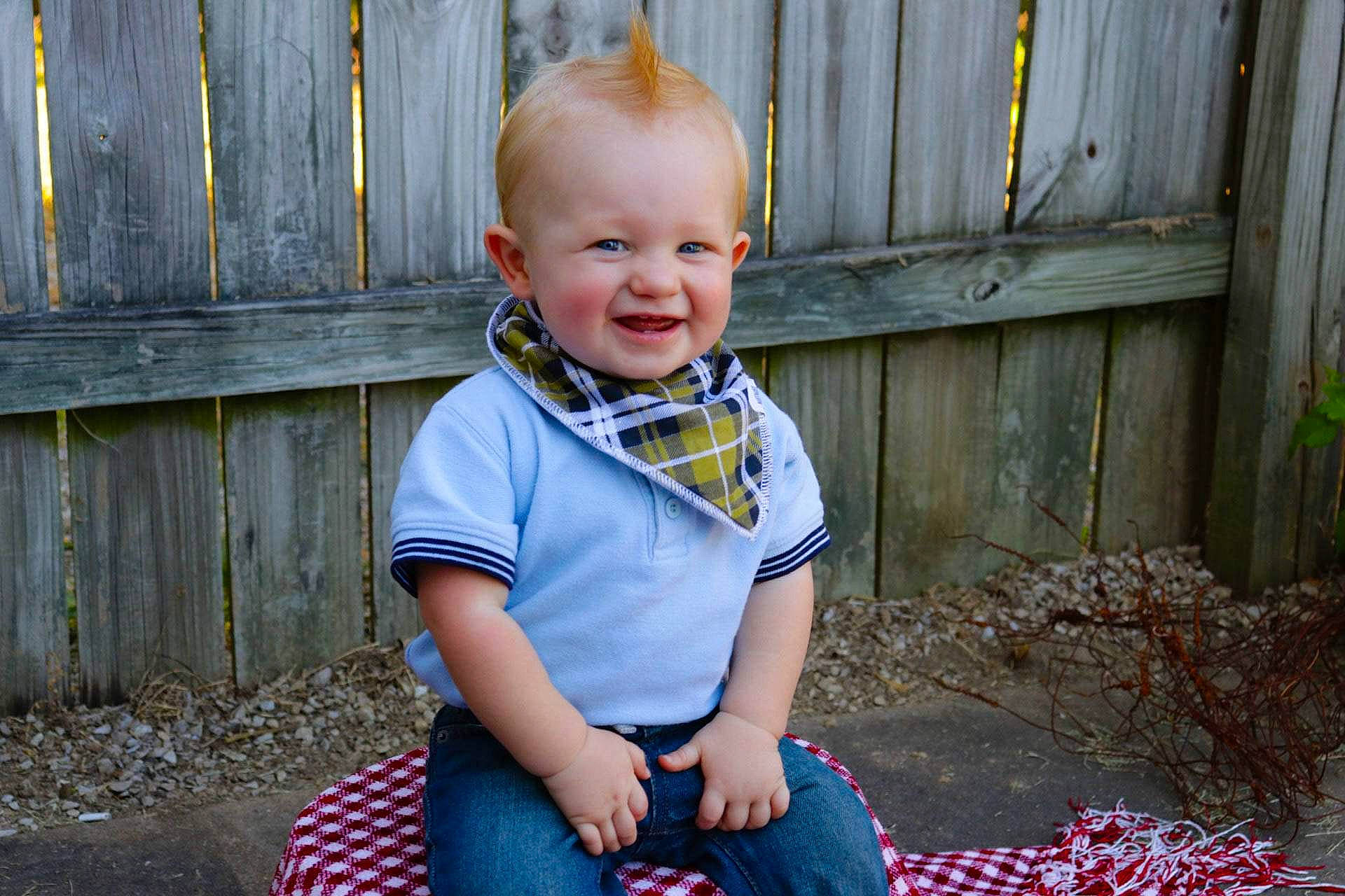 Finnegan is registered to the contest to win money with this photo: baby_toddler_clothing, blue, cheek, child, dress, eye, face, grass, joy, leaf, pattern, people, person, photograph, photography, plaid, portrait_photography, sitting, skin, smile