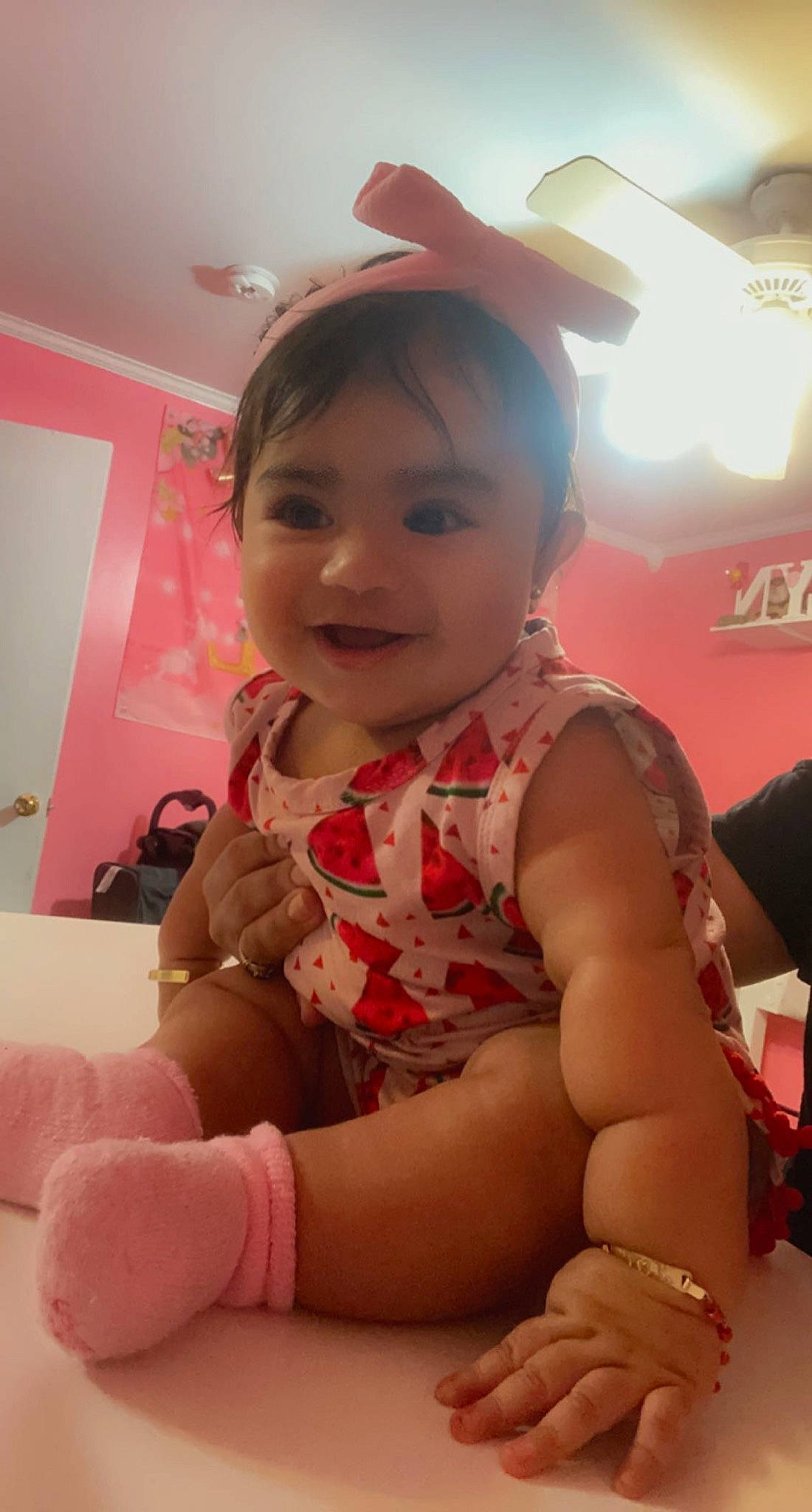 Jocelyn is registered to the contest to win money with this photo: baby, baby_toddler_clothing, child, dress, fashion_accessory, finger, flooring, fun, happy, human_leg, jewellery, joy, neck, person, pink, room, sitting, skin, smile, thigh