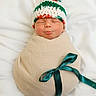 newborn, baby, sleeping, wrapped, blanket, ribbon, knitted_hat, pom_pom, green, white, red, soft, cute, infant, portrait, cozy, resting, child, peaceful, indoors