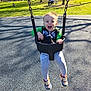 Jonathan is registered to the contest to win money with this photo: toddler, child, swing, playground, park, happy, smiling, outdoor, daylight, casual_clothing, sneakers, green_jacket, plastic_swing, trees, grass, people, bench, sunlight, shadow, fun