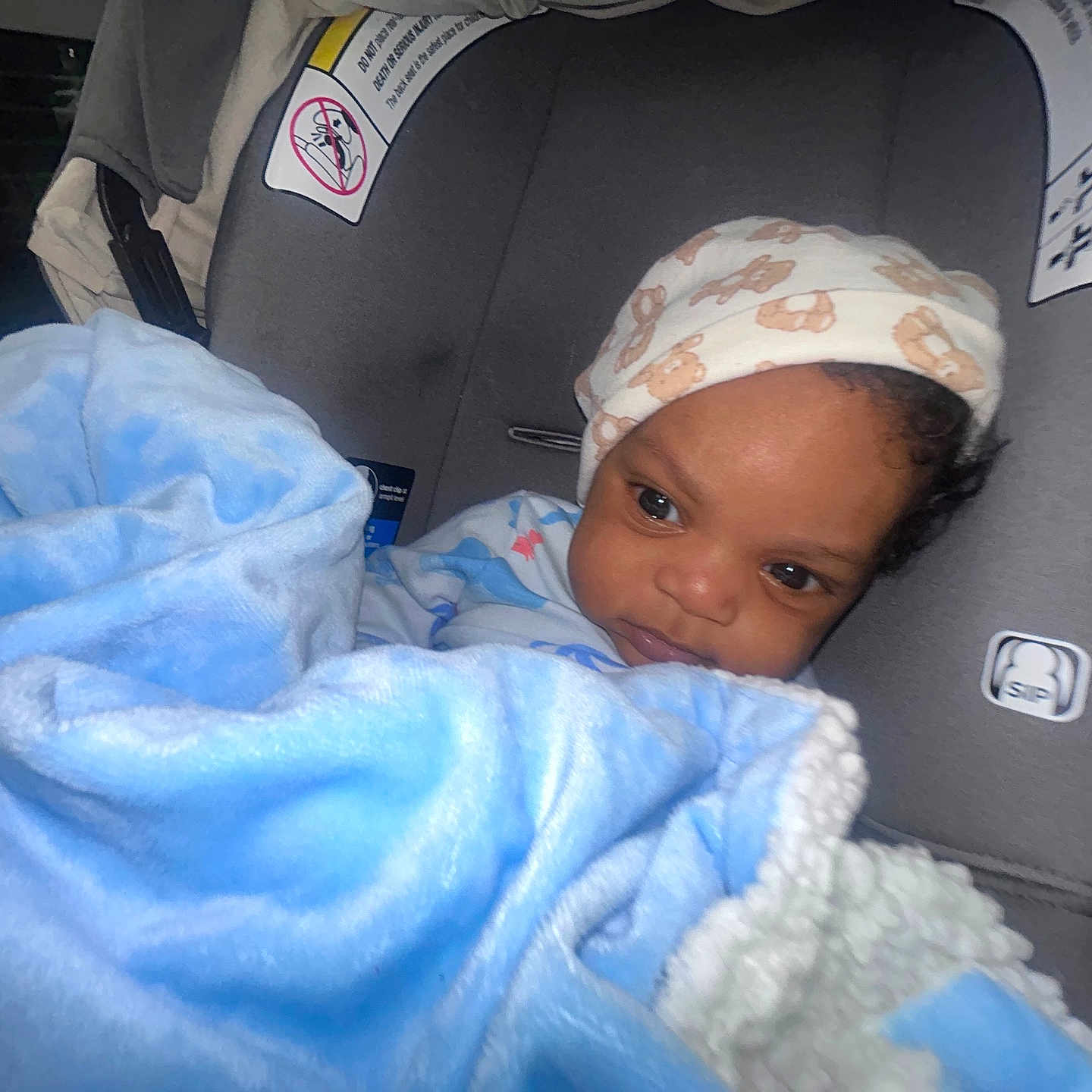 Austin is registered to the contest to win money with this photo: baby, blanket, blue, car_seat, child, clothing, comfort, cute, face, hat, indoor, infant, person, portrait, seat, soft, toddler, warm, wearing, young