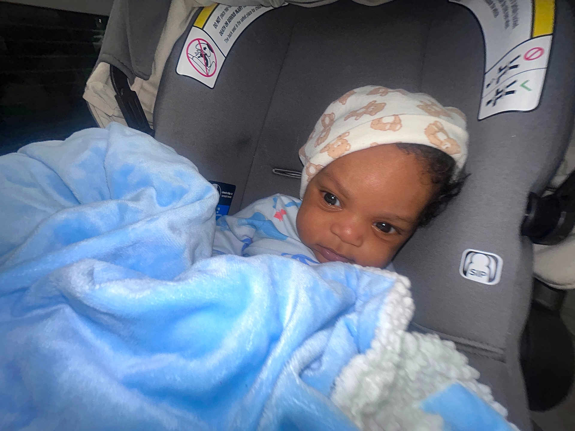 Austin is registered to the contest to win money with this photo: baby, blanket, car_seat, hat, child, face, infant, clothing, blue, comfort, cute, indoor, person, portrait, seat, soft, warm, young, toddler, wearing