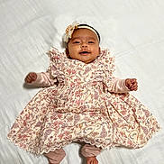 Evana joined the competition — help win amazing prizes! baby, infant, smiling, dress, floral_pattern, headband, lying_down, white_blanket, happy, cute, child, portrait, indoors, soft_lighting, small_hands, small_feet, fabric, patterned_clothing, adorable, ruffles