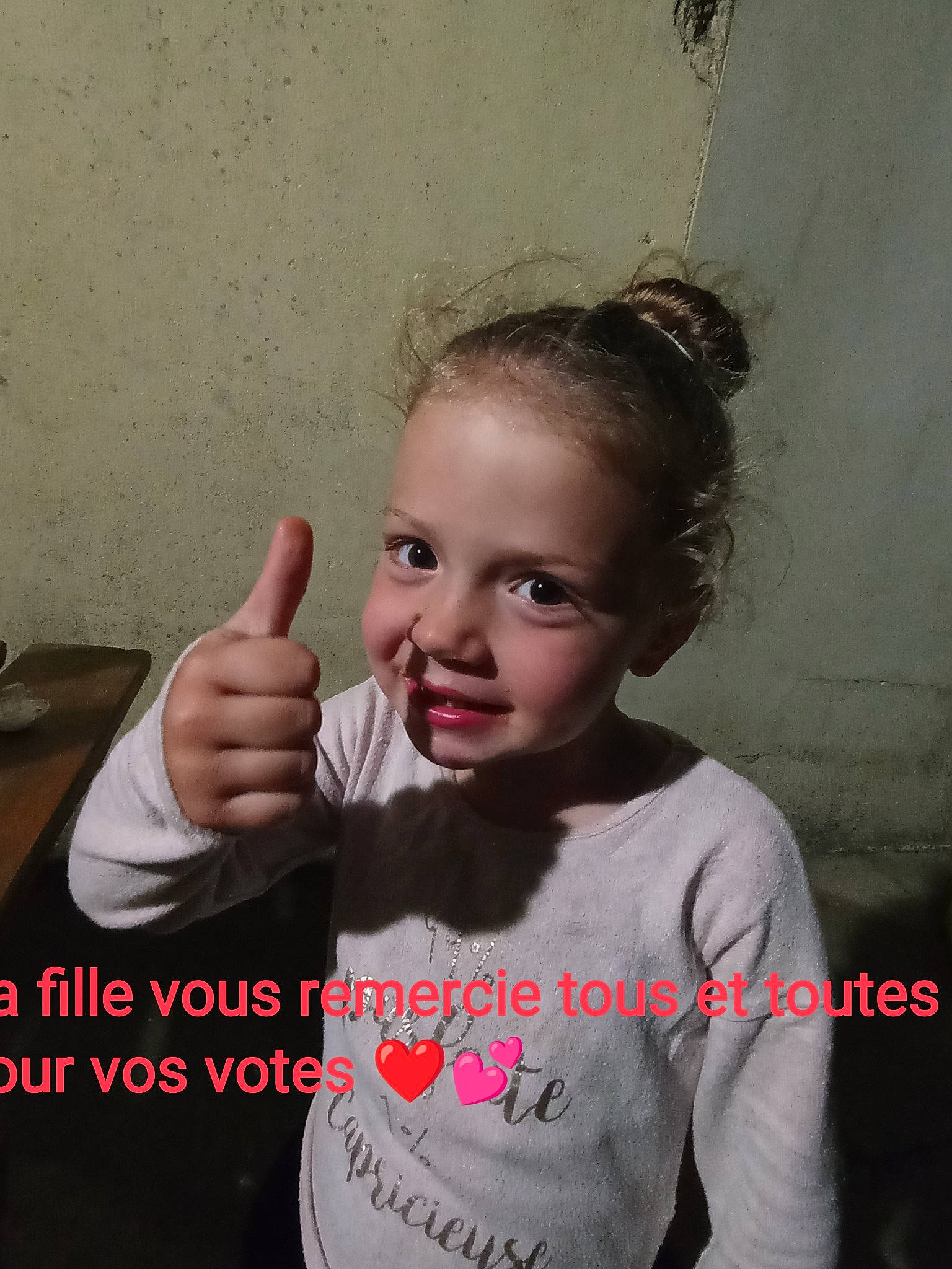 Maëlynn participe au concours pour gagner de l'argent avec cette photo : arm, eyebrow, face, flash_photography, forehead, fun, gesture, hand, happy, joint, neck, person, shoulder, sign_language, sleeve, smile, standing, t_shirt, thumb, toddler