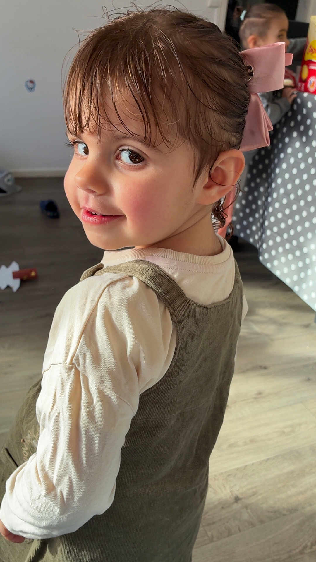 Maëvis a rejoint le concours — aidez-le/la à gagner de superbes lots ! child, toddler, girl, hair_bow, bow, portrait, smile, looking_back, dress, pinafore, long_sleeve, indoor, hardwood_floor, polka_dot, reflection, mirror, toy, rosy_cheeks, eyelashes, candid