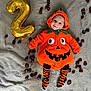 baby, child, costume, pumpkin, orange, striped_socks, balloon, number_two, blanket, gray, chestnuts, cute, smiling, hoodie, celebration, autumn, holiday, lying_down, face, festive