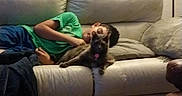 Juno joined the competition — help win amazing prizes! child, cat, sofa, couch, sleeping, lounging, indoor, living_room, pet, animal, kitten, human, portrait, relaxed, green_shirt, blue_pants, pillows, blanket, family, nap