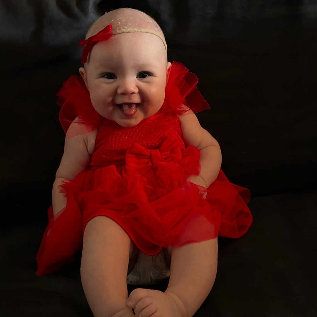 Willow is registered to the contest to win money with this photo: baby, bodypart, clothing, couch, dress, eveningdress, face, finger, formalwear, furniture, hand, happy, hat, head, newborn, person, photography, portrait, sitting, smile