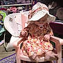Raven is registered to the contest to win money with this photo: car_seat, chair, child, dress, ear, furniture, hat, headgear, pink, rocking_chair, sitting, sun_hat, toddler