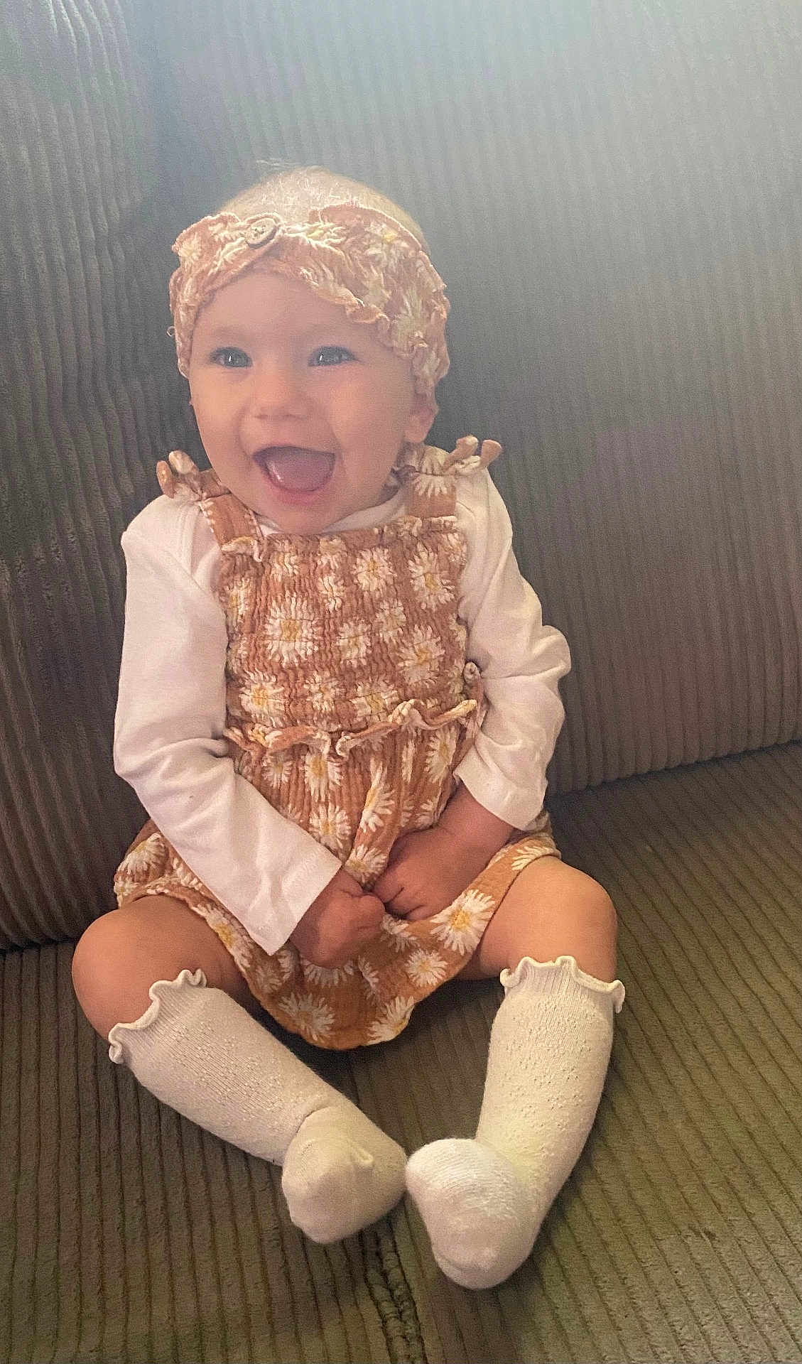 Alynnah is registered to the contest to win money with this photo: baby, child, smiling, headband, socks, couch, seated, happy, portrait, clothing, infant, cute, indoors, person, fabric, textured, daisy_pattern, long_sleeve, casual, young