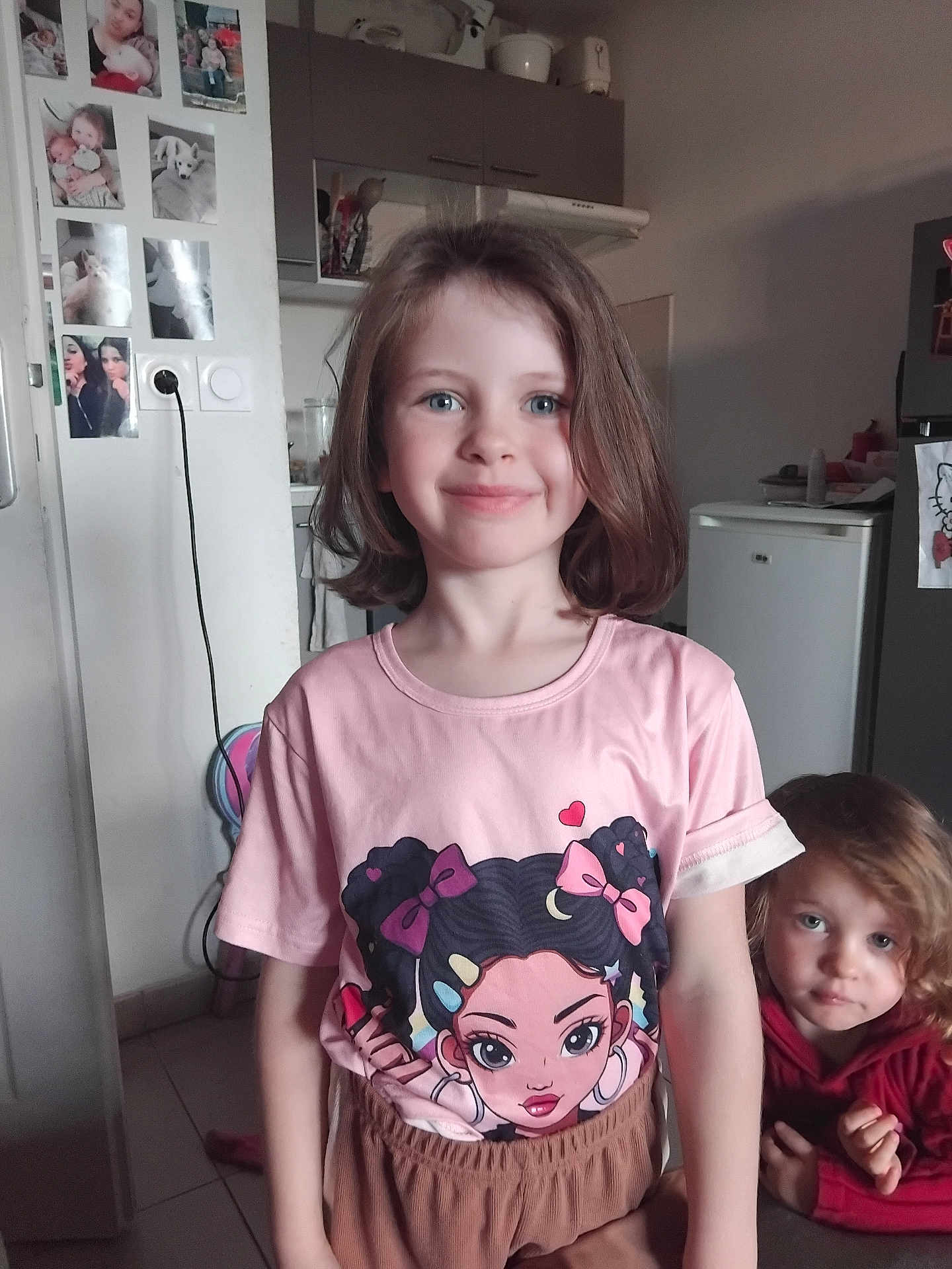 Inaya participe au concours pour gagner de l'argent avec cette photo : child, children, girl, toddler, smile, indoor, kitchen, clothing, pink_tshirt, brown_pants, short_hair, curly_hair, cute, portrait, two_children, home, family, happy, playful, casual