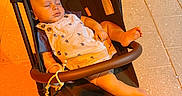 Beau is registered to the contest to win money with this photo: baby, stroller, sleeping, child, overalls, footwear, toddler, outdoor, sidewalk, tile_floor, sunlight, peaceful, cute, infant, seat, resting, baby_clothes, legs, hand, daytime