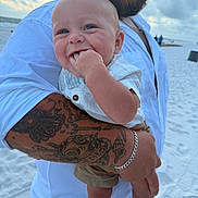 Beau joined the competition — help win amazing prizes! baby, child, man, tattoo, beach, sand, sky, clouds, blue_eyes, smile, chewing, holding, white_shirt, bracelet, portrait, outdoor, person, happy, summer, family
