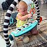 Beau is registered to the contest to win money with this photo: baby, child, toy, play, indoor, floor, piano, colorful, yellow_clothing, carpet, plastic_toy, foot, hand, face, person, furniture, living_room, curious, playful, black_and_white_stripes