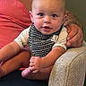 Beau is registered to the contest to win money with this photo: baby, infant, child, person, face, arm, hand, foot, bib, clothing, tattoo, sitting, couch, fabric, skin, indoor, portrait, expression, holding, curious