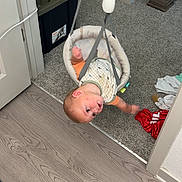 Beau is registered to the contest to win money with this photo: baby, doorway_jumper, infant, carpet, floor, doorway, clothing, indoor, child, play, suspended, curious, expression, home, wood_floor, plastic, fabric, toy, baby_gear, childcare