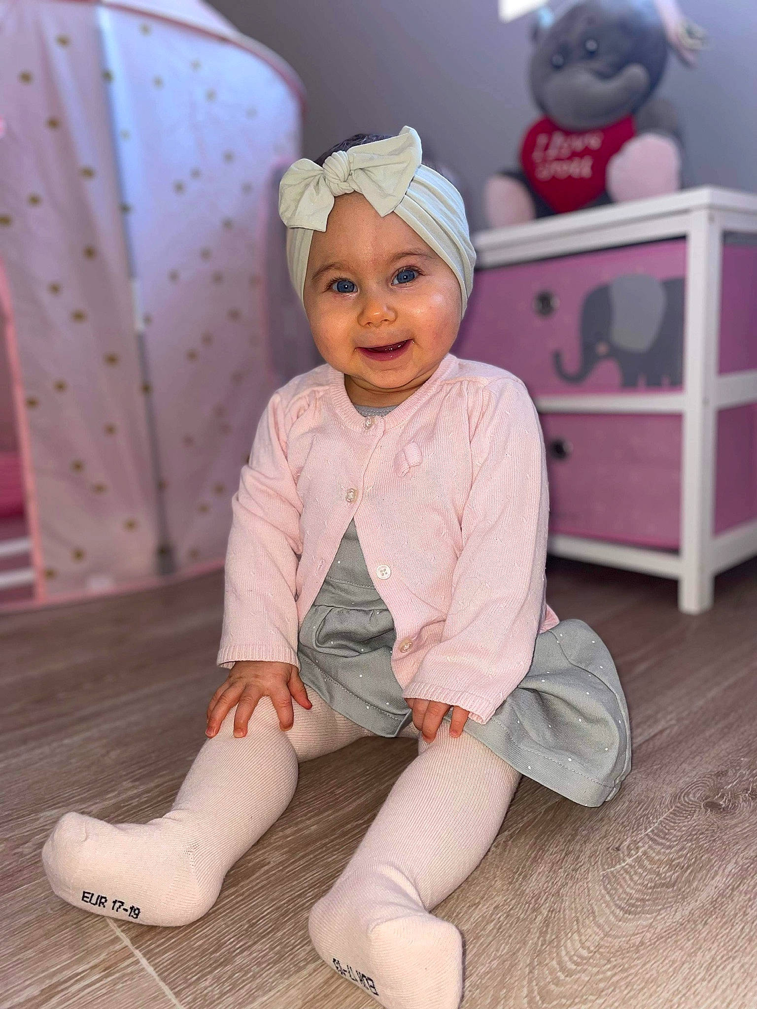 Leiya a rejoint le concours — aidez-le/la à gagner de superbes lots ! baby_toddler_clothing, barefoot, child, floor, flooring, foot, happy, hardwood, headwear, human_leg, joy, knee, person, pink, purple, sleeve, smile, textile, thigh, toddler
