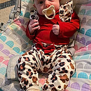 Aurora joined the competition — help win amazing prizes! baby, infant, pacifier, headband, leopard_print, red_clothing, socks, colorful_cushion, cartoon_backdrop, rainbow, indoor, seated, child, cute, soft_lighting, patterned_pants, comfort, portrait, expression, baby_seat