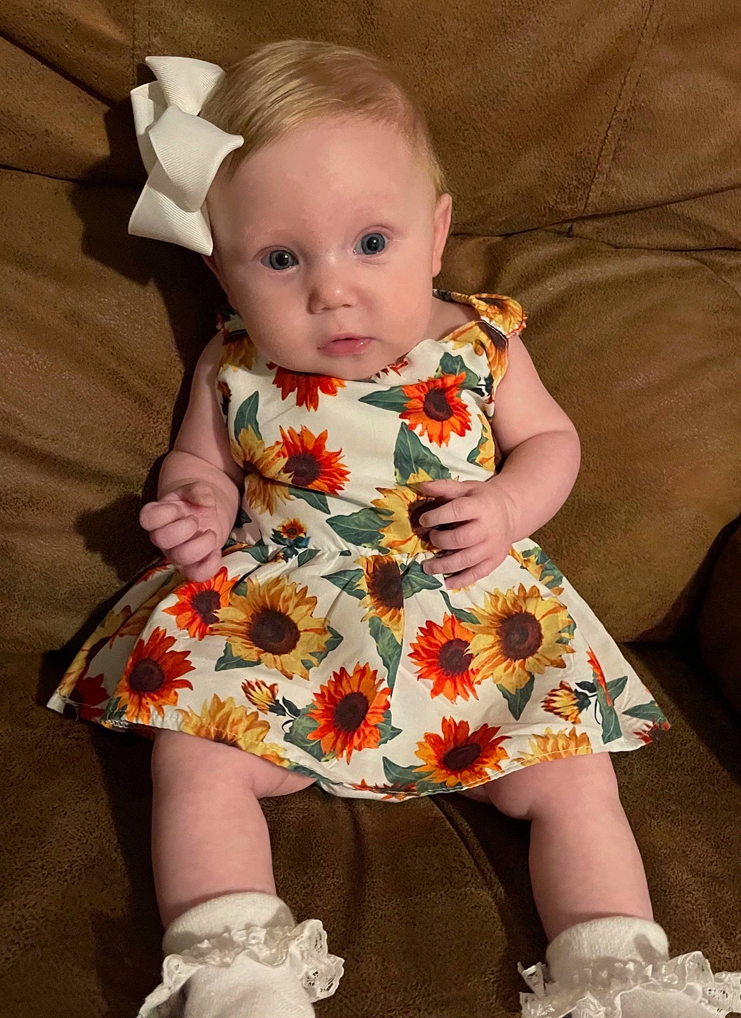 Everly Rose is registered to the contest to win money with this photo: baby, baby_toddler_clothing, cheek, child, day_dress, dress, eye, hand, head, human_body, iris, neck, one_piece_garment, pattern, person, pink, sitting, skin, sleeve, textile