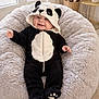baby, infant, plush, panda_costume, onesie, hood, smile, beanbag, cozy, nursery, indoor, sitting, cute, chubby_cheeks, soft, blanket_like, lamp, pampas_grass, hardwood_floor, portrait