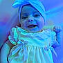 baby, infant, smiling, headwrap, dress, bow, cute, happy, portrait, closeup, child, blue_light, purple_light, fabric, clothing, face, eyes, hand, skin, indoors