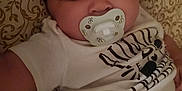 Jada is registered to the contest to win money with this photo: baby, child, closeup, clothing, cute, expressionless, fabric, face, hugs, indoors, infant, lying_down, pacifier, pants, patterned_background, small_child, soft_lighting, white_shirt, young_child, zebra_design