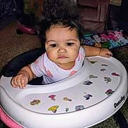 Jada joined the competition — help win amazing prizes! baby, walker, child, indoor, furniture, carpet, clothing, person, hair, face, hand, toy, sticker, pink, white, sitting, expression, curly_hair, foot, home