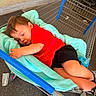 black_shorts, blanket, blue_sippy_cup, child, clothing, cozy, cute, floor, footwear, head, indoors, person, red_shirt, relaxation, resting, shopping, shopping_cart, sleeping, toddler, toy