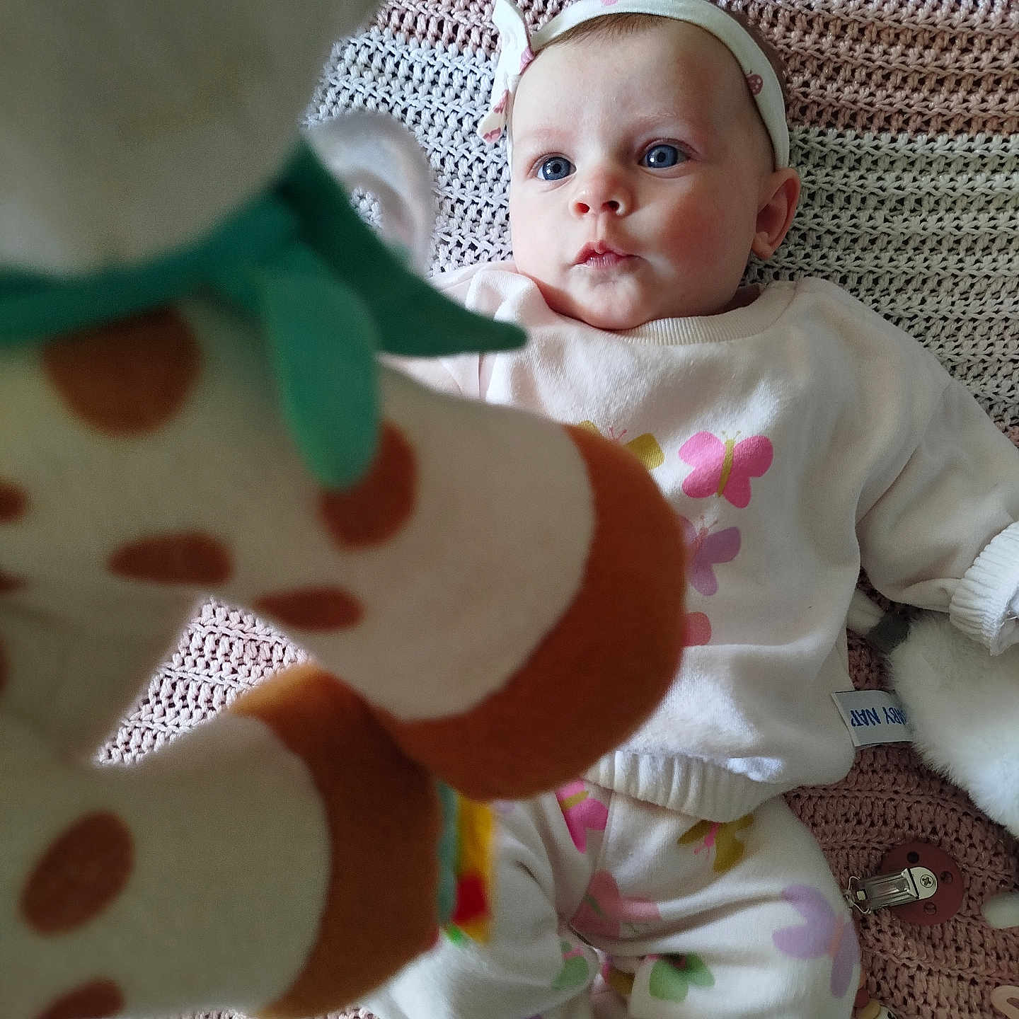 Maëlya participe au concours pour gagner de l'argent avec cette photo : baby, blue_eyes, headband, knitted_blanket, lying_down, soft_toy, giraffe_toy, white_clothing, colorful_patterns, infant, cute, indoors, child, playful, focus, toy, baby_girl, fabric, face, closeup