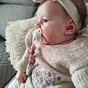Maëlya participe au concours pour gagner de l'argent avec cette photo : baby, pacifier, headband, knit_sweater, floral_embroidery, pillow, couch, indoor, child, cozy, soft_texture, seated, cute, infant, side_profile, casual_clothing, relaxed, small_hand, comfort, portrait