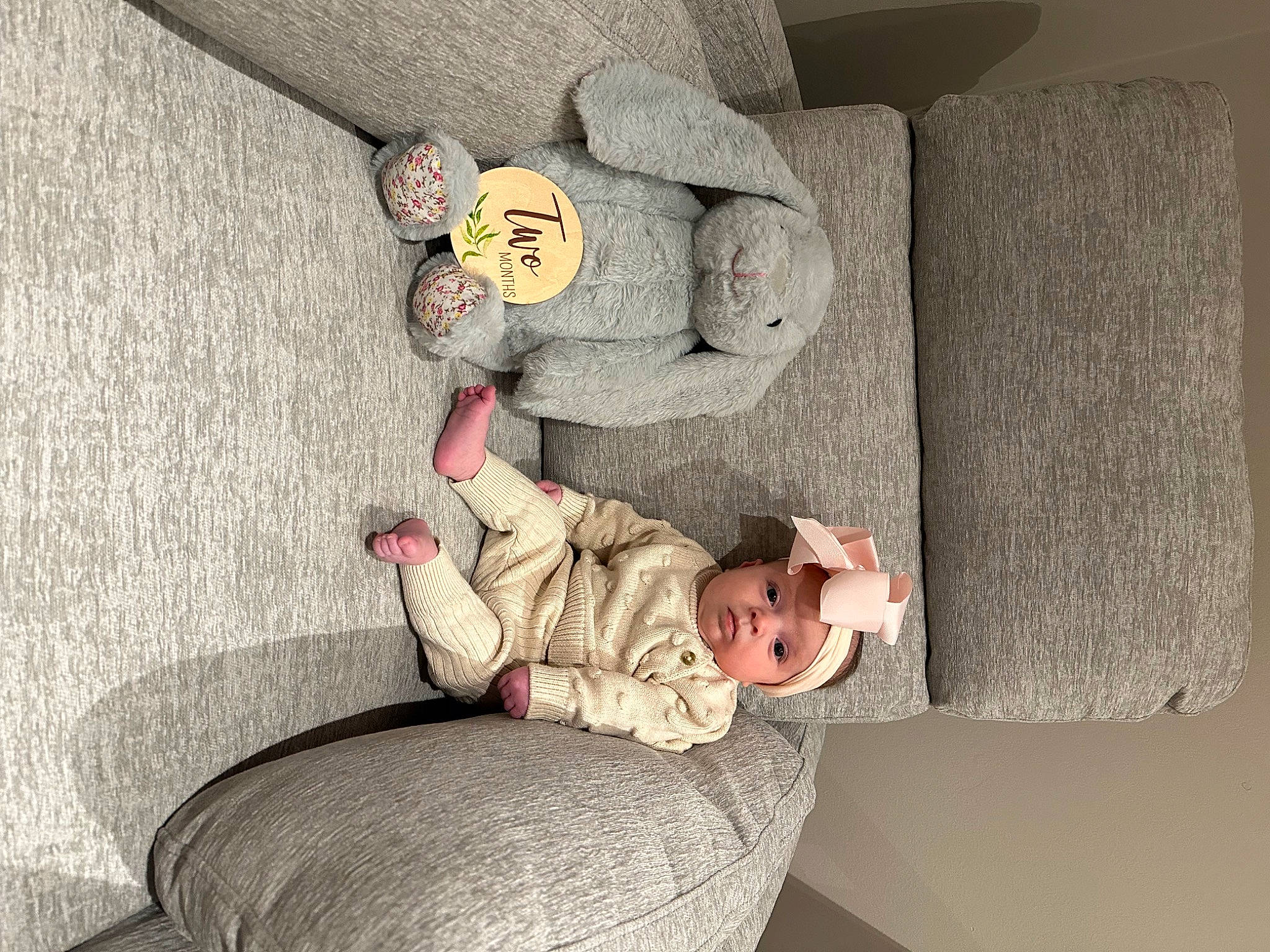 Hadley is registered to the contest to win money with this photo: art, baby, baby_toddler_clothing, chair, child, comfort, couch, furniture, grey, headwear, linens, living_room, person, room, sitting, stuffed_toy, teddy_bear, toddler, toy, wall