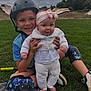 child, baby, boy, helmet, protective_gear, knee_pads, grass, outdoor, smile, headband, sweater, playground, skate_park, happy, siblings, casual_clothing, fun, nature, daytime, park