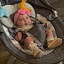 baby, baby_booties, baby_rocker, child, cushion, expression, flooring, footwear, furniture, headband, indoor, infant, moon_toy, person, pink_bow, seat_belt, smile, star_toy, toy, wood_floor