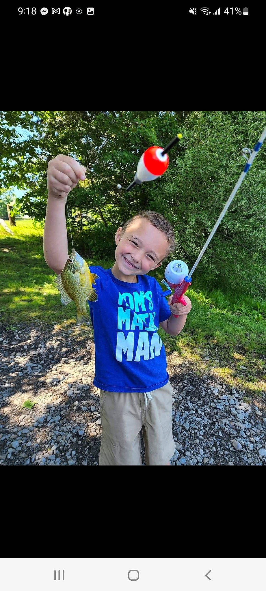 Declan is registered to the contest to win money with this photo: child, electric_blue, fish, fun, gesture, grass, happy, joy, leaf, leisure, people_in_nature, person, plant, recreation, smile, soil, t_shirt, thumb, toddler, toy