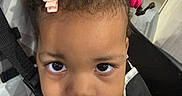 Harmony is registered to the contest to win money with this photo: toddler, child, baby, face, eyes, hair, pink_bow, pink_hair_ties, stroller, seatbelt, clothing, indoor, portrait, curious, young_child, expression, person, closeup, infant, candid