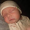 Lilly is registered to the contest to win money with this photo: baby, sleeping, infant, hat, onesie, closeup, face, peaceful, soft, texture, warm_lighting, newborn, cute, resting, child, portrait, skin, cozy, comfort, indoor