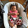Alana is registered to the contest to win money with this photo: baby, infant, child, baby_seat, pink_bib, ladybug_skirt, curly_hair, white_bow, indoor, wooden_floor, carpet, footwear, socks, hands, face, expression, cushion, seat_belt, toy, person