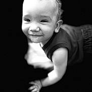 Deiondre joined the competition — help win amazing prizes! baby, child, crawling, smiling, black_and_white, portrait, face, infant, cute, happy, young, skin, hair, eyes, expression, hand, clothing, dark_background, closeup, person