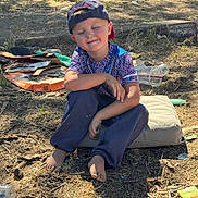 Gunnar joined the competition — help win amazing prizes! child, boy, outdoor, barefoot, cap, sitting, smiling, closed_eyes, cushion, trash, plastic_cup, pizza_box, dry_ground, grass, sunlight, casual_clothing, recreation, nature, relaxation, daytime