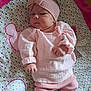 baby, infant, pink_clothing, headband, patterned_blanket, lying_down, cute, small_hands, soft_fabric, indoors, child, newborn, cozy, sleepwear, headwear, person, portrait, colorful, comfort, resting