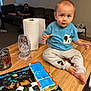 Jacob Corona is registered to the contest to win money with this photo: toddler, child, cake, table, frosting, blue_frosting, orange_frosting, mickey_mouse, clothing, face, person, indoor, living_room, couch, man, paper_towel, glass, foot, smudged, curious