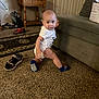Jacob Corona joined the competition — help win amazing prizes! baby, child, indoor, carpet, couch, table, water_jug, rug, shoe, sock, onesie, furniture, living_room, floor, person, curious, crawling, cushion, wooden_table, home