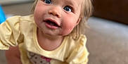 Navy is registered to the contest to win money with this photo: toddler, child, baby, crawling, blue_eyes, pink_bow, yellow_dress, carpet, indoor, cute, smiling, face, hand, foot, clothing, person, portrait, home, curious, playful