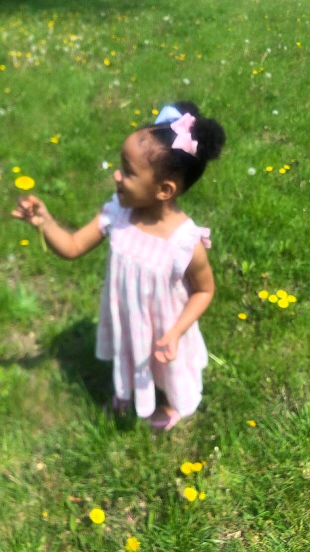 Amoura is registered to the contest to win money with this photo: baby_toddler_clothing, botany, dress, finger, flower, fun, gesture, grass, grass_family, grassland, hand, happy, leaf, meadow, people_in_nature, person, petal, plant, summer, sunlight