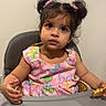 Elaina Amirah Beloua is registered to the contest to win money with this photo: toddler, child, high_chair, pink_dress, pigtails, food, waffle, indoor, wall, drawing, curious, cute, person, portrait, young_child, hair_accessories, colorful, sitting, looking_up, baby