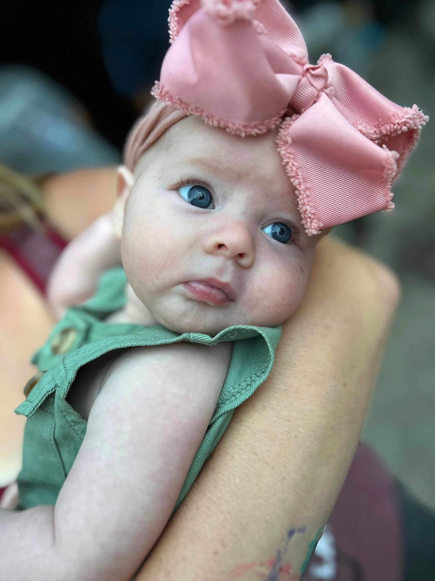 Maesyn joined the competition — help win amazing prizes! baby, infant, child, blue_eyes, pink_bow, headband, green_outfit, close_up, portrait, arm, holding, cute, skin, person, young_child, face, expression, soft_focus, outdoor, gentle