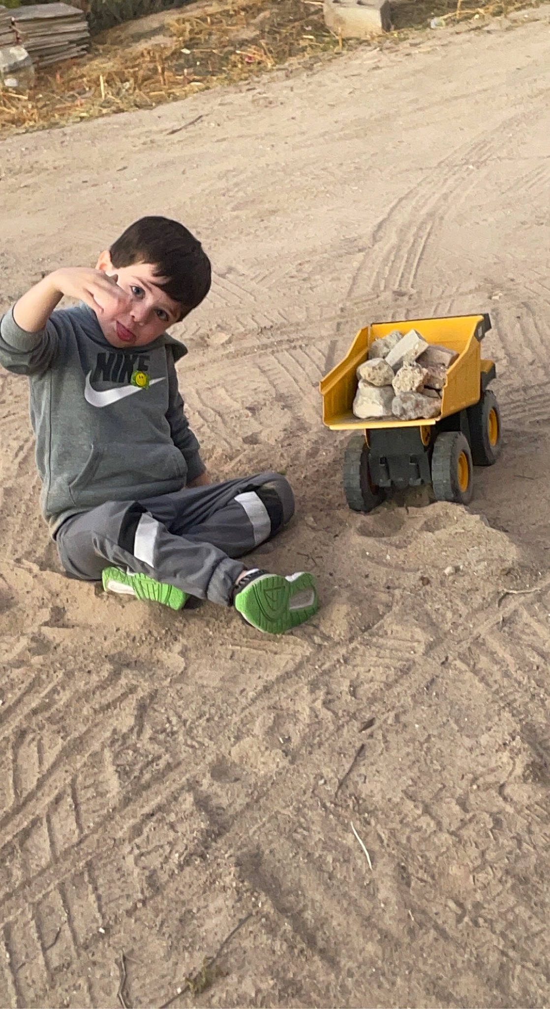 Brayden is registered to the contest to win money with this photo: adaptation, asphalt, automotive_tire, baseball_cap, fun, geological_phenomenon, geology, grass, hat, landscape, motor_vehicle, person, recreation, sitting, soil, tire, toddler, travel, truck, wheel